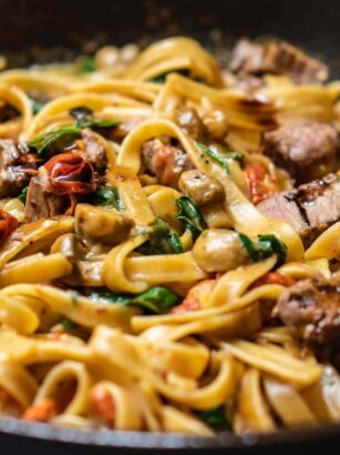 Linguine with pancetta, mushrooms, tomatoes and herbs sautéed in a skillet.