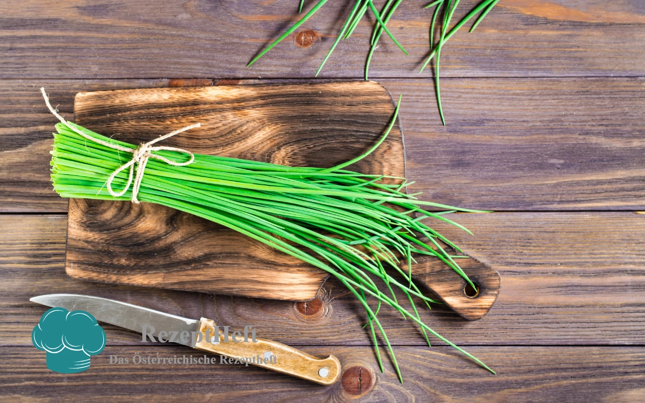 Schnittlauch_Titelbild | RezeptHeft Bund frischer Schnittlauch gebunden auf einem Holzschneidebrett, daneben ein Messer – rustikaler Küchenstil.
