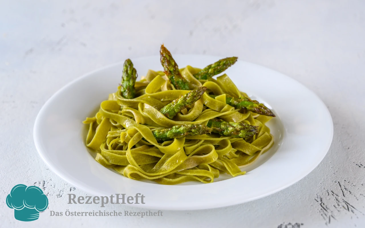 Green tagliatelle pasta with roasted asparagus on a white plate