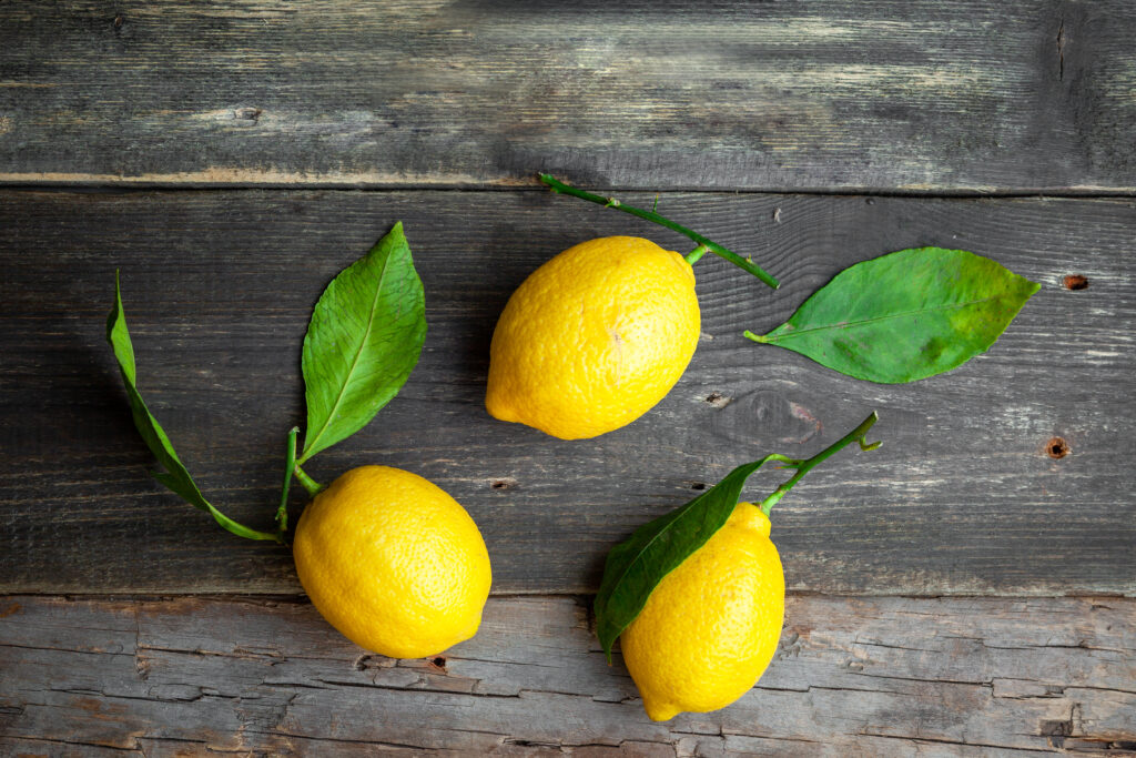 Lemons with leaves top view on a dark wooden background | RezeptHeft Zitronen